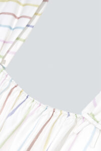 A detailed shot of the ruched neckline on MANITO rainbow stripe dress.