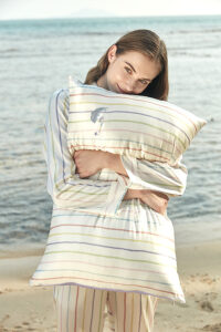 Model hugging the MANITO striped silk pillowcase, showcasing its soft texture and delicate embroidery.