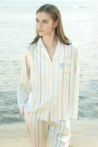 Model wearing MANITO rainbow striped long sleeve shirt and pants by the ocean.