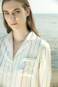 Close-up of a model in MANITO rainbow striped long sleeve shirt with dolphin embroidery on the chest pocket.