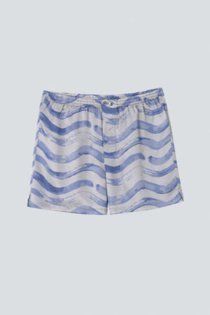 Flat lay of MANITO Ocean Wave Men's Shorts featuring blue wave patterns on light gray silk.
