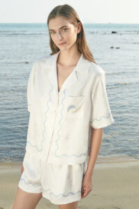 Front view of MANITO Ocean Wave Silk Women's Short Pajama Set featuring wave patterns and dolphin embroidery by the sea.