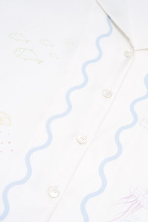 Detailed shot of fish and wave print along the button line on the MANITO Ocean Wave Silk Women's Short Pajama Set.