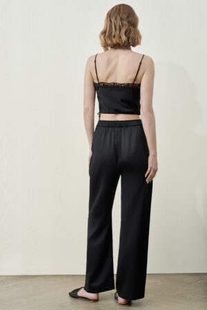 Back view of MANITO Passion Women's Silk Trousers in black, styled with a lace-detailed black camisole.