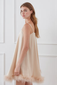 Side view of Diva Feather Women's Trimmed Short Slip Dress in champagne with feather hem and adjustable straps.