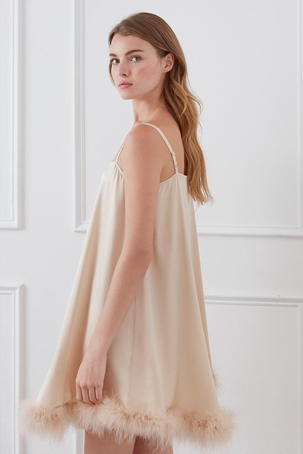 Side view of Diva Feather Women's Trimmed Short Slip Dress in champagne with feather hem and adjustable straps.
