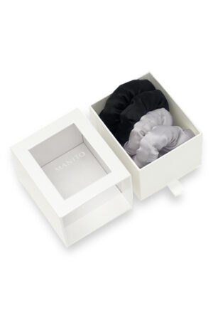 White gift box containing black and gray puff silk hair scrunchies with the lid placed on the side.