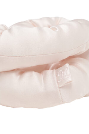 Close-up of a pink puff silk hair scrunchie showing the small MANITO logo tag.