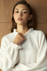 Close-up of woman wearing Purity Drawstring Set in snow white, showing a soft ruffled neckline and smooth texture.