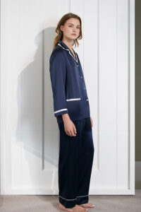 Model in a navy Coco Lady Silk Pajama Set accented with white piping for a stylish bedtime ensemble.