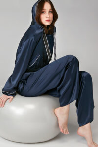 Woman wearing Sportif Silk Tracksuit in navy, featuring MANITO logo hood drawstrings and contrast piping details.