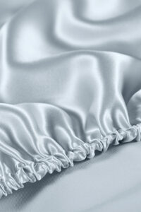 Exquisite close-up of soft blue silk fabric with delicate ruched detailing highlighting the lustrous texture and quality.