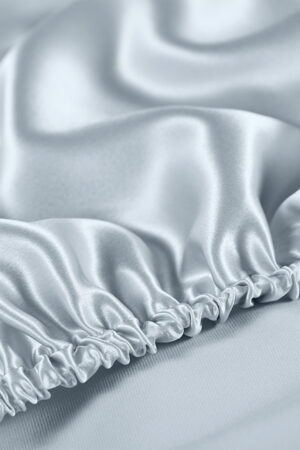 Exquisite close-up of soft blue silk fabric with delicate ruched detailing highlighting the lustrous texture and quality.