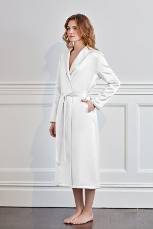 Stylish woman presenting a white silk terry robe with sophisticated trim.
