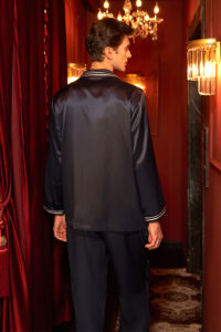 Back view of navy MANITO Ribbon Men's Pajama Set in silk under chandelier lighting.
