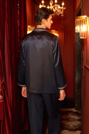 Back view of navy MANITO Ribbon Men's Pajama Set in silk under chandelier lighting.