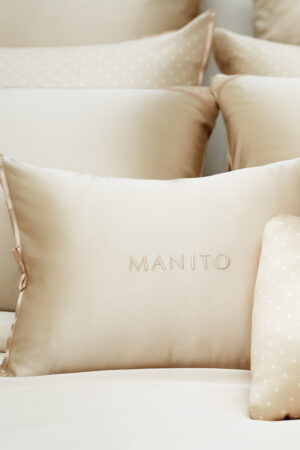 Embroidered MANITO pillow with a matching polka dot duvet cover, adding a refined touch to the bedding set.