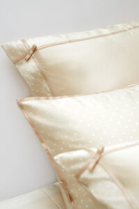 A closer look at the MANITO pillowcases with ribbon accents, complementing the soft, polka dot silk duvet cover.