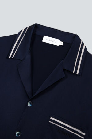 Collar and chest pocket detail of navy MANITO Ribbon pajama shirt with striped trim.