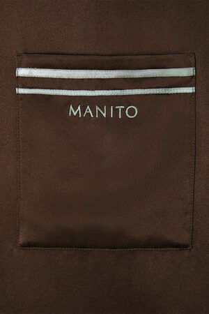 Chest pocket of MANITO Ribbon pajama shirt in brown with embroidered logo and stripe accents.