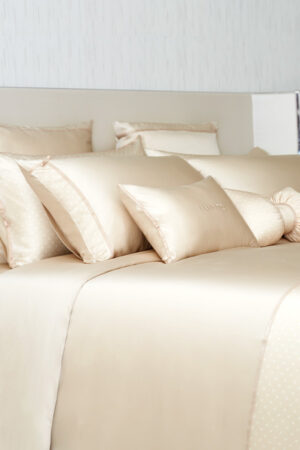 Luxurious MANITO silk pillowcases with ribbon accents and soft polka dots, adding sophistication to the bedroom decor.