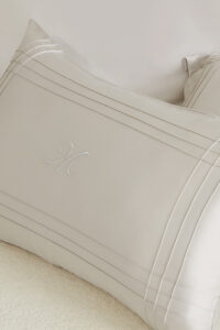 Close-up of MANITO Ripple Bedding Set pillowcase featuring elegant embroidery and refined silk detailing.