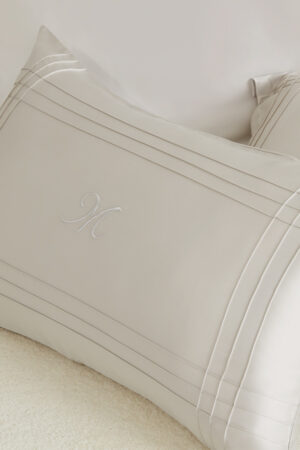 Close-up of MANITO Ripple Bedding Set pillowcase featuring elegant embroidery and refined silk detailing.