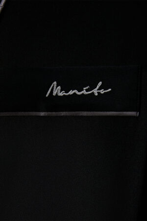 A close-up of the MANITO logo on Rome Men's Black Silk Robe.