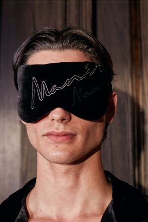 Man wearing a black velvet MANITO Rome Velvet Silk Eye Mask, promoting restful sleep.