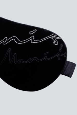 Detailed embroidery on a black velvet sleeping mask showcasing the elegant MANITO signature.