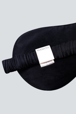 Close-up of a MANITO-branded tag on a black velvet sleeping mask, symbolizing quality and comfort.