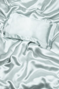 Silk pillowcase on draped silk sheets conveying luxury and comfort.