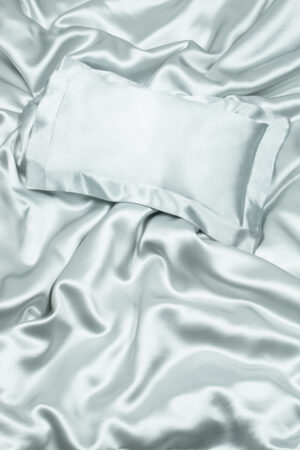 Silk pillowcase on draped silk sheets conveying luxury and comfort.
