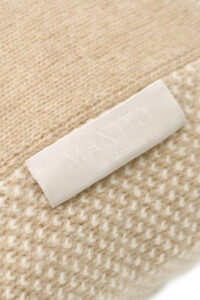 Close-up of Sand Dune Knit Pillow label with MANITO logo, highlighting fine craftsmanship and texture.