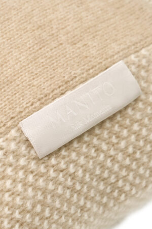 Close-up of Sand Dune Knit Pillow label with MANITO logo, highlighting fine craftsmanship and texture.