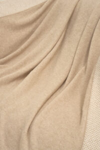 Detailed view of Sand Dune Knit Throw Blanket fabric, showing its smooth drape and natural sheen.