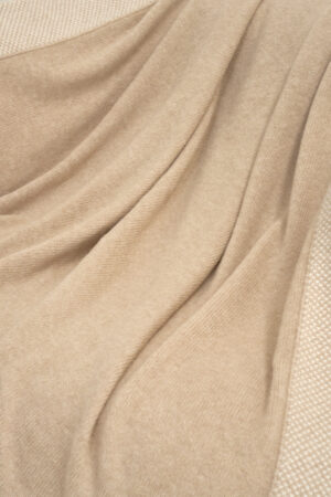 Detailed view of Sand Dune Knit Throw Blanket fabric, showing its smooth drape and natural sheen.