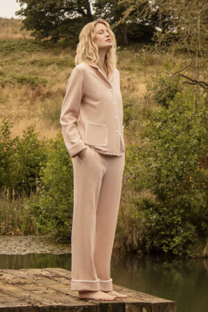 A woman is standing on an ourdoor wooden dock in Shell Women's Cashmere Pink Lounge Set.