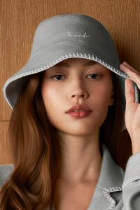 Model wears Shell Women's Silk Wool Bucket Hat in grey with curved brim and delicate embroidered detailing.