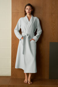 Woman wears blue Shell Silk Wool Robe, full-length front view with wrap front and belt for calm rest.