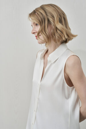 Side profile of MANITO Signature Women's Silk Sleeveless Shirt in white highlighting sharp collar detail.