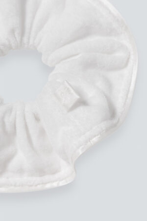 MANITO Silk Terry Scrunchie with a focus on the tag displaying the embroidered "M" logo.
