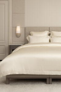 Luxurious MANITO Silver Wire Silk Duvet Cover set on a king-sized bed, featuring jacquard silver silk fabric and a gold trim.
