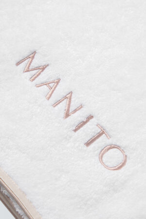 MANITO Soft Feeling 3 Pieces Bath Towel Set close-up of embroidered logo on white cotton towel with silk trim.
