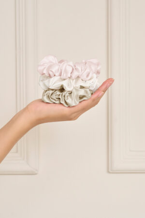 Hand holding the Sweet Garden Silk Hair Scrunchies Set-Three in Ballet Pink, Almond Beige, and Champagne Gray.