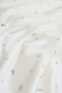 Sweet Garden Silk Throw showcasing close-up draped silk with subtle Sweet Garden floral patterns for a refined texture.