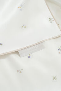 Sweet Garden Silk Throw detailed view highlighting the MANITO label, smooth silk surface, and floral print accents.