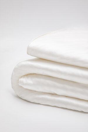 Close-up of a cream silk filled duvet, elegantly folded showing the plush and luxurious texture for a cozy bedroom setting.