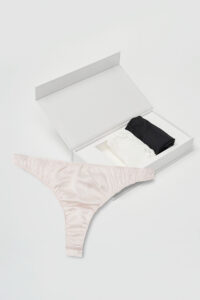 Black and white Tacetto briefs stacked inside the opened gift box with a pink one displayed in front, emphasizing sleek silk comfort.