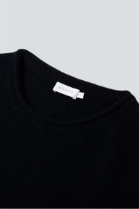 Close-up of MANITO Teddy black classy elastic knit lounge set neckline, showing soft knit texture and brand label.